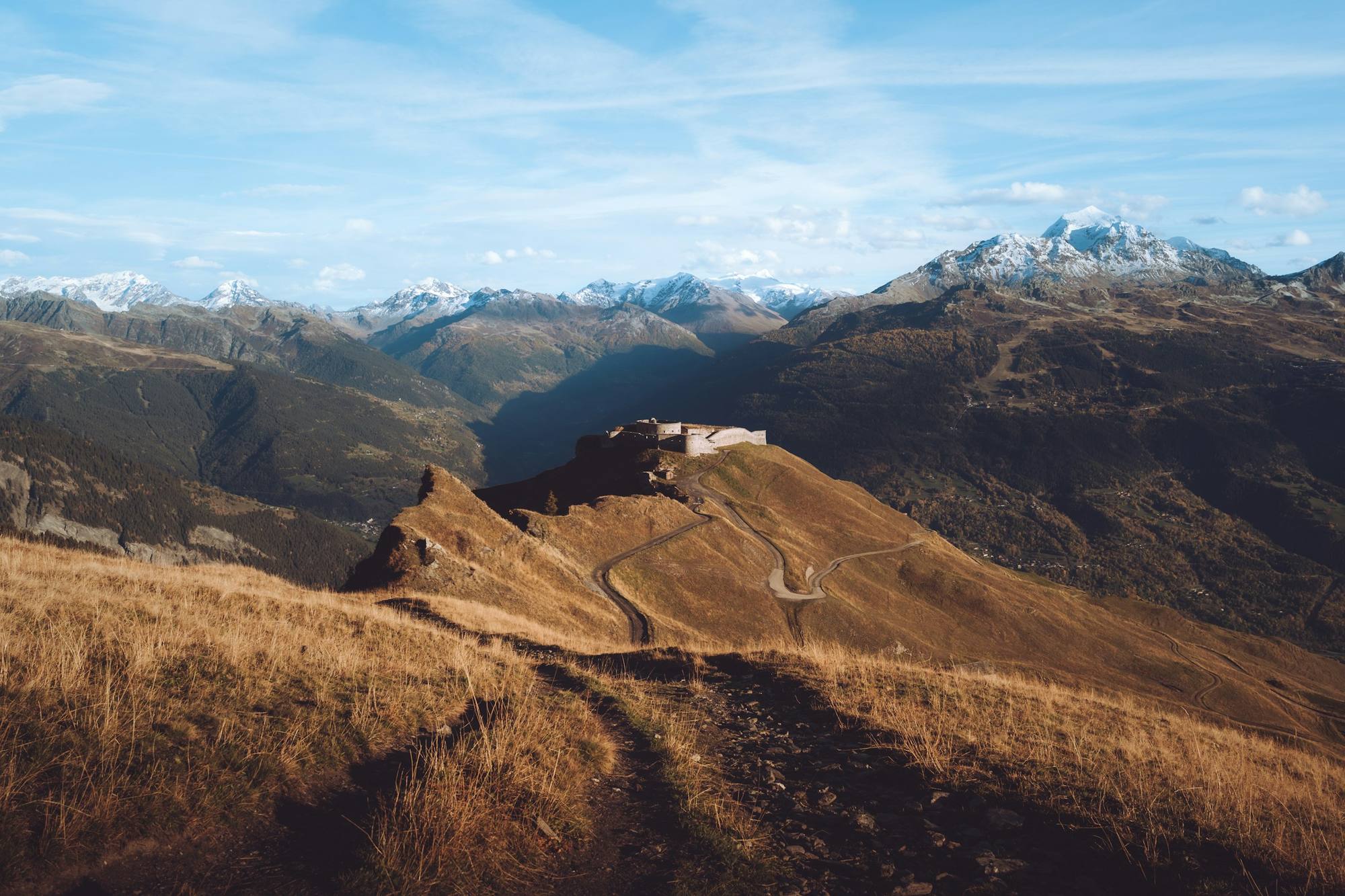 Das Fort de la Platte auf seinem rotbraunen Grasrücken über dem Tal von Bourg-Saint-Maurice, gegenüber den verschneiten Gipfeln